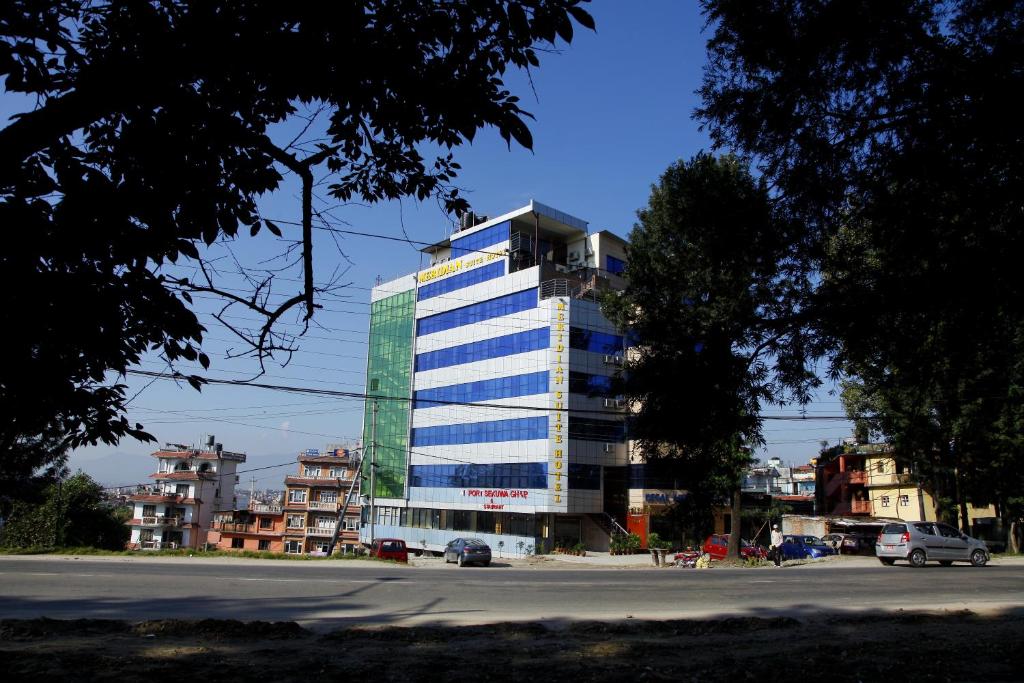 un edificio alto con ventanas azules en una calle de la ciudad en Hotel Meridian Suite, en Katmandú