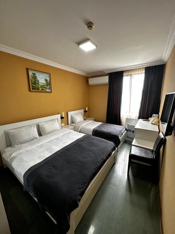 Habitación de hotel con 2 camas y escritorio en Hotel Brighton, en Batumi