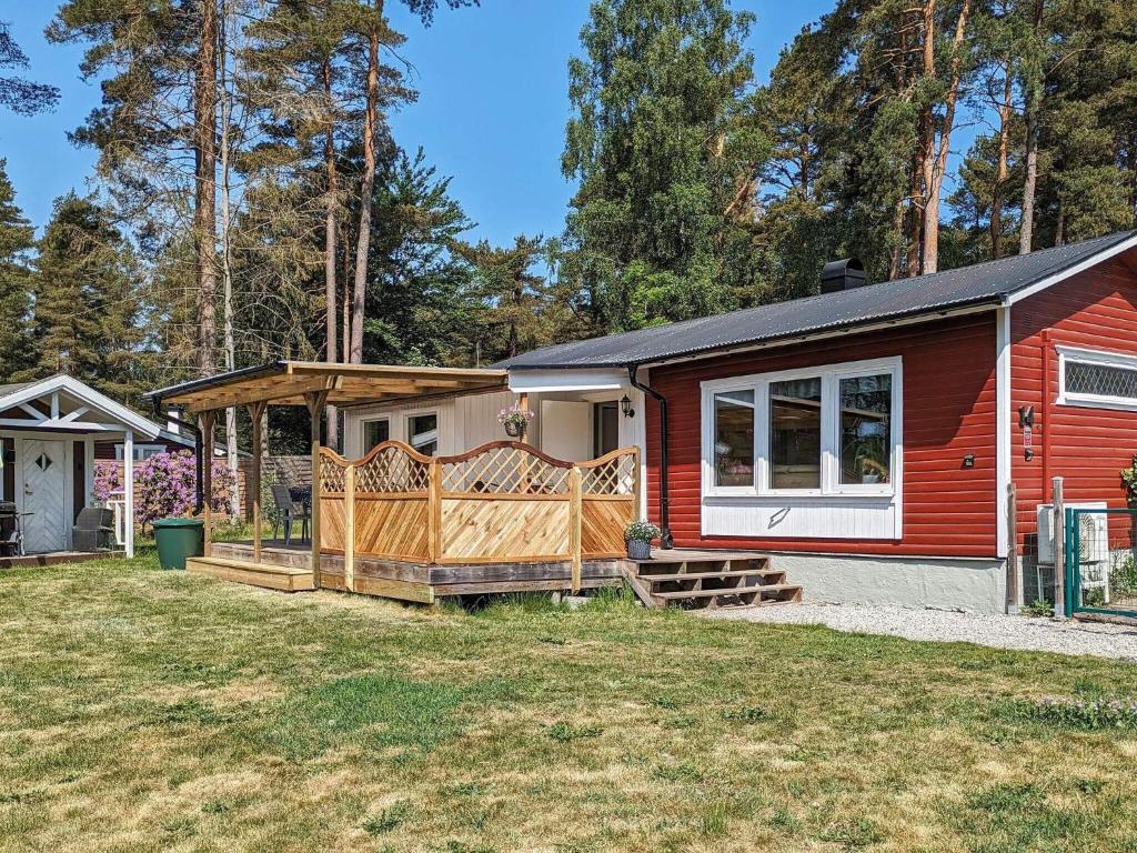 una pequeña casa roja con porche y patio en Holiday home SJÖBO, en Sjöbo