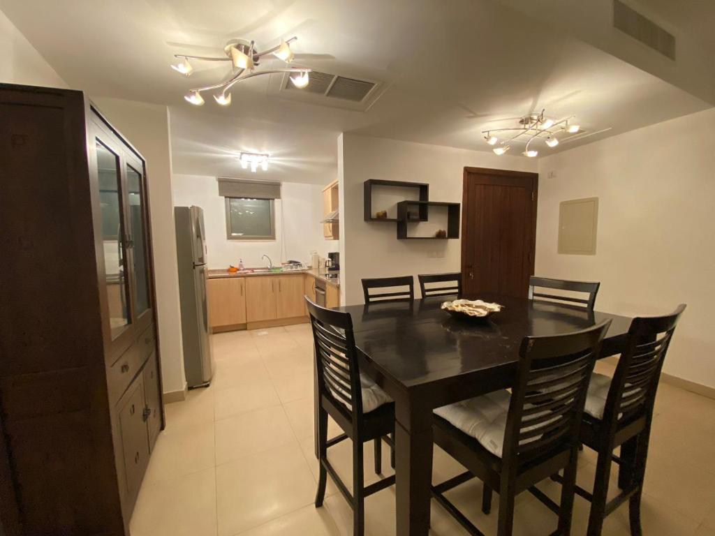 a kitchen and dining room with a table and chairs at Lovely first floor tow bed rooms overviewing circular pool for families only in Talabay Aqaba in Aqaba