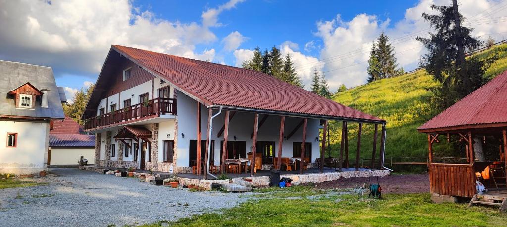 une maison avec un toit rouge et une montagne dans l'établissement Pensiunea Trei Brazi Arieseni, à Arieşeni