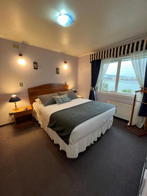 a bedroom with a large bed and a large window at Montepiedra Costanera Valdivia in Valdivia