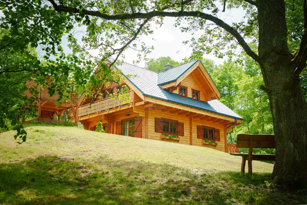 uma casa de madeira no topo de uma colina com um banco em Rodinná roubenka U Tří skřítků em Cervena Voda