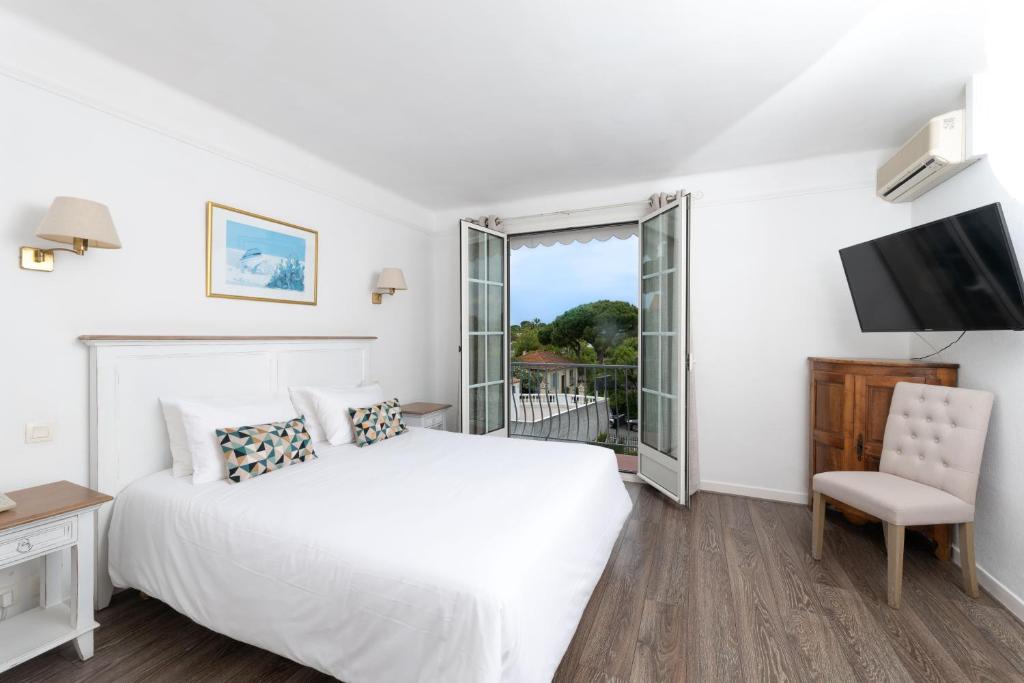 a white bedroom with a bed and a television at Hôtel Beau Site - Cap d'Antibes in Antibes