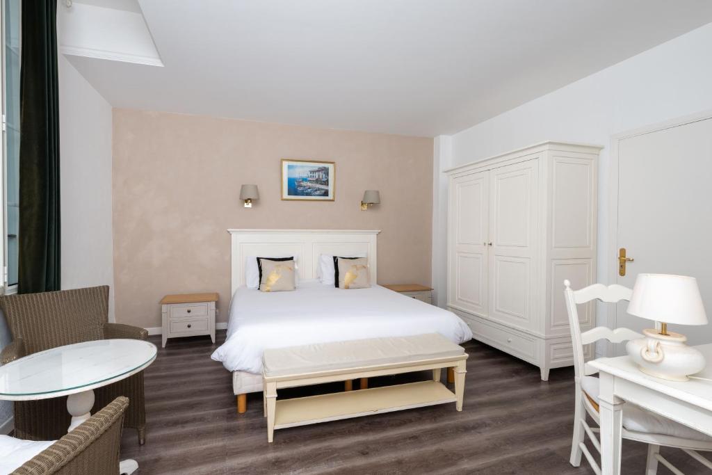 a bedroom with a white bed and a table at Hôtel Beau Site - Cap d'Antibes in Antibes