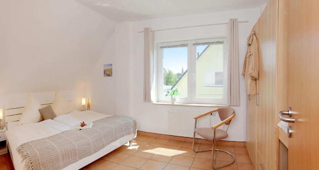 ein Schlafzimmer mit einem Bett, einem Fenster und einem Stuhl in der Unterkunft MEERerholung in Zinnowitz