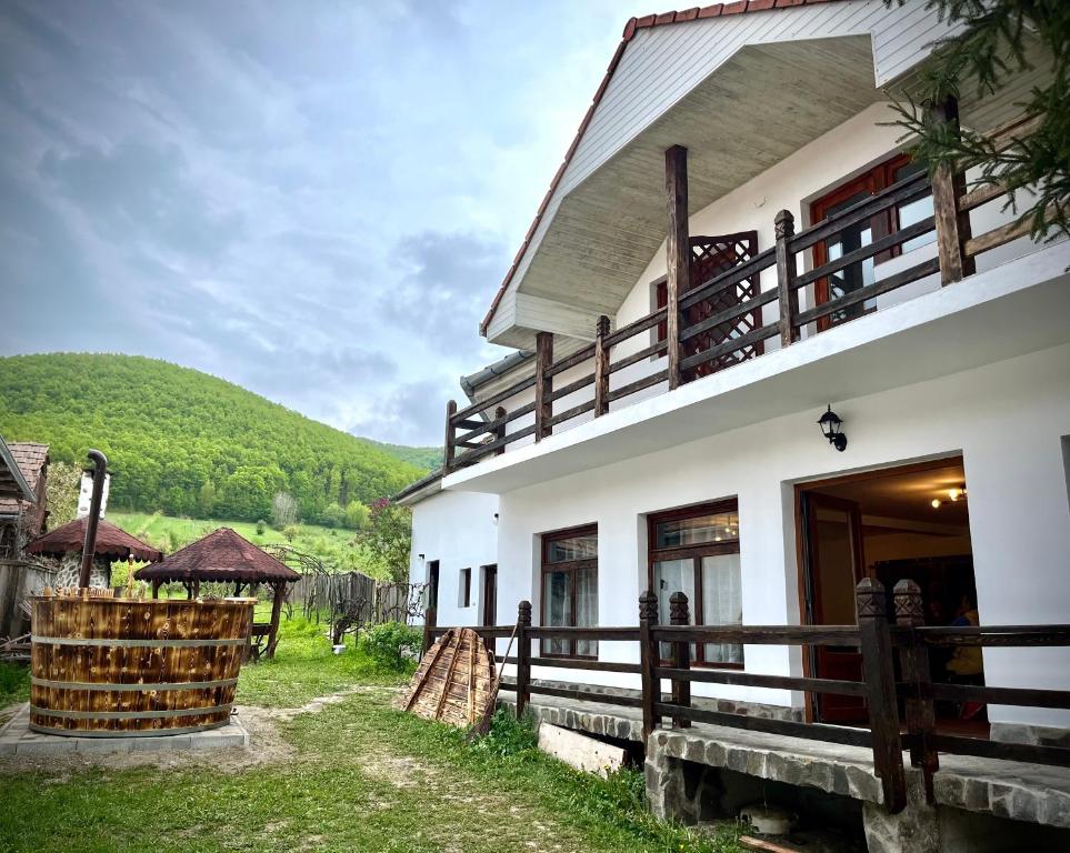 a white building with a fence next to a field at Casa Ariana in Poiana Aiudului