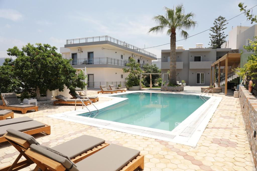 a swimming pool with chaise lounge chairs and a building at Maria Apartments in Hersonissos