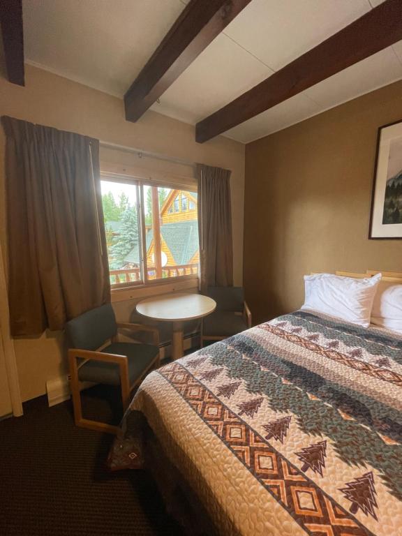 a hotel room with a bed and a table and a window at Spirit Lake Lodge in Grand Lake