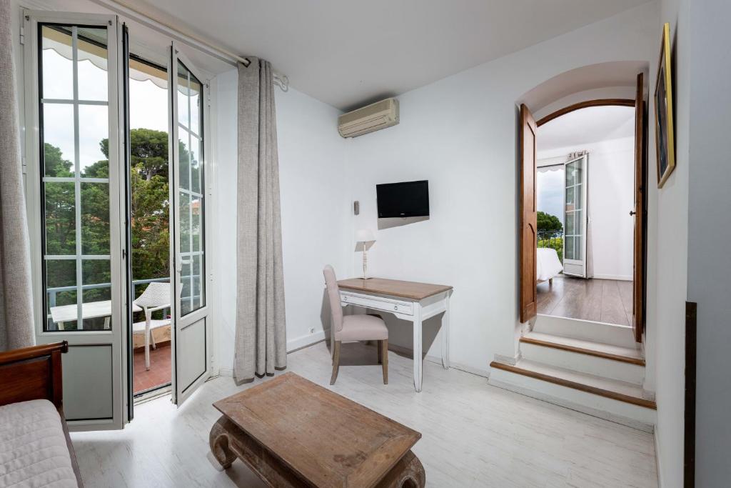 a living room with a table and a desk at Hôtel Beau Site - Cap d'Antibes in Antibes