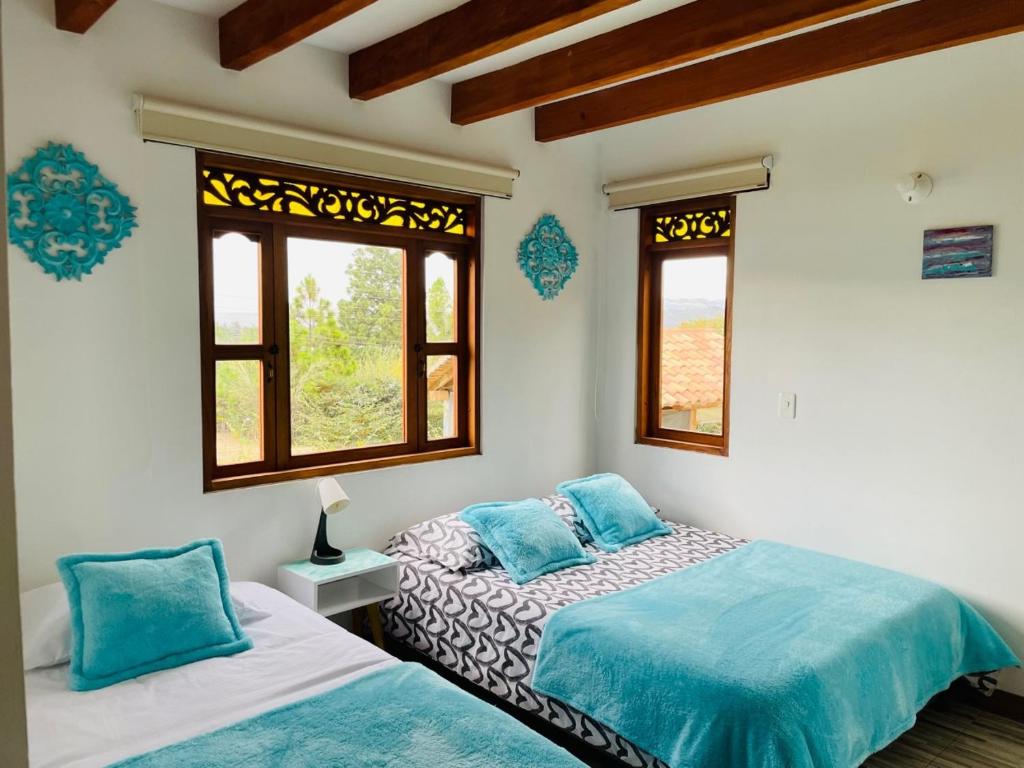 1 dormitorio con 2 camas y 2 ventanas en Casa turquesa, en Villa de Leyva