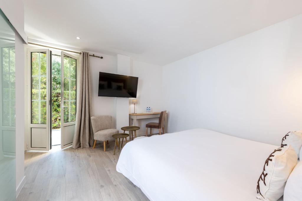 a white bedroom with a bed and a table and chairs at Hôtel Beau Site - Cap d'Antibes in Antibes
