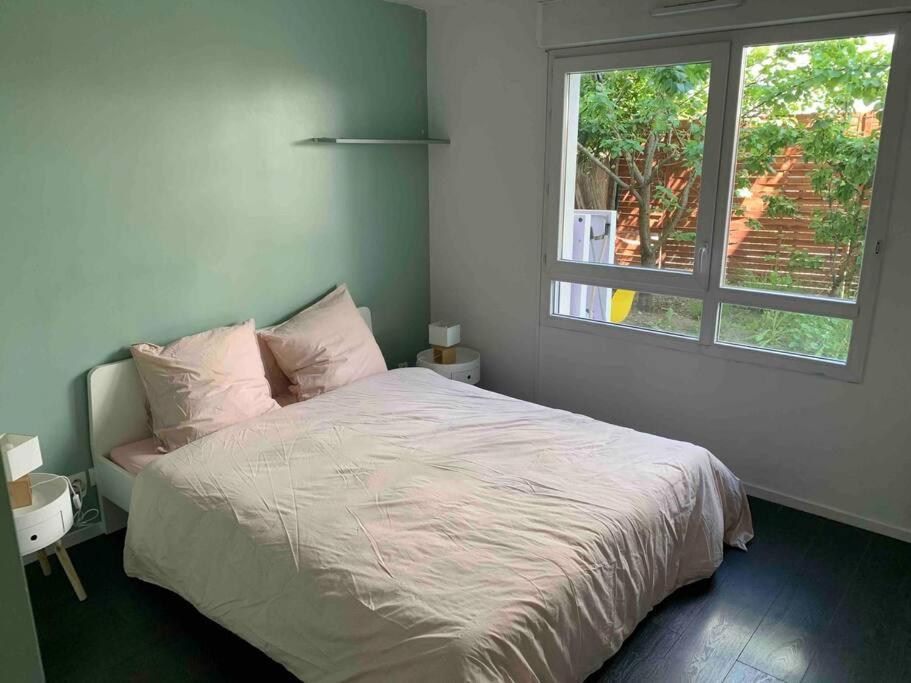 1 dormitorio con 1 cama grande y ventana en Bel appartement terrasse+jardin en La Courneuve