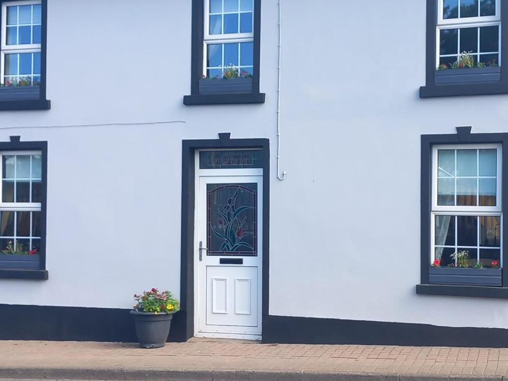 un edificio blanco con una puerta y dos ventanas en Appletree lodge, en Dungiven