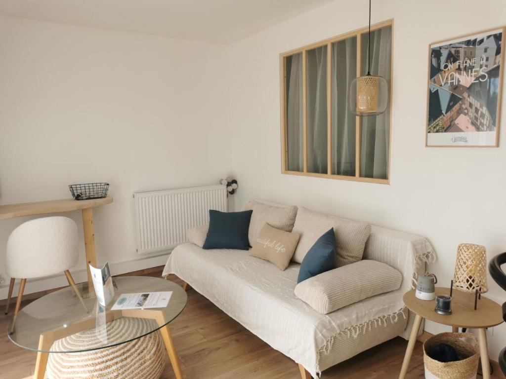 ein weißes Wohnzimmer mit einem Sofa und Tischen in der Unterkunft Appartement cosy Le Saint Gildas, à proximité immédiate centre ville, place de stationnement, Netflix in Vannes