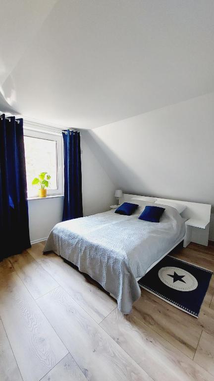 Schlafzimmer mit einem Bett mit blauen Vorhängen und einem Fenster in der Unterkunft Villa Azalia in Jastrzębia Góra