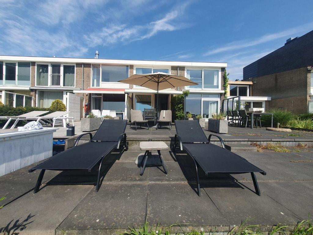een groep tafels en een paraplu voor een gebouw bij Cosy holiday home on Lake Veere with the beach right at your doorstep in Kamperland