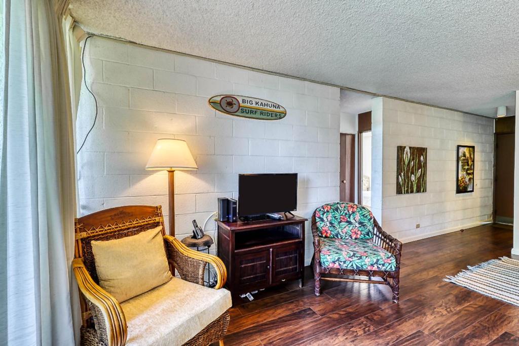 uma sala de estar com um sofá, uma televisão e uma cadeira em Maunaloa Shores 612 em Hilo