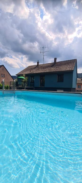 a large pool of blue water in front of a house at Maison piscine in Saint-Amarin