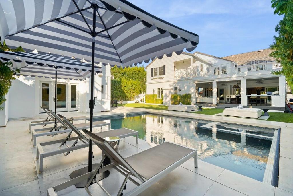 a pool with chairs and an umbrella next to a house at Hearst Estate in Los Angeles