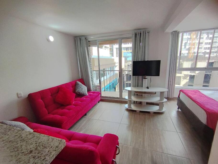 a living room with a red couch and a bed at Espectacular Aparta Estudio Armenia Quindío in Armenia