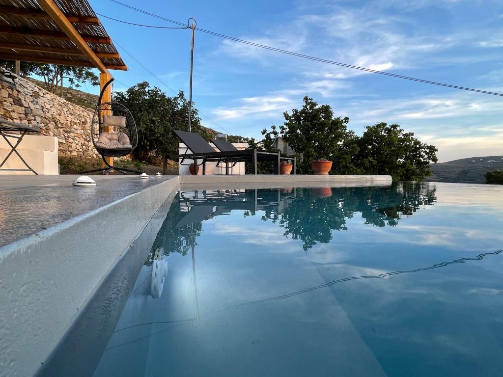 a swimming pool with the reflection of the sky in the water at Euphoria Tinos Suite in Skaládhos