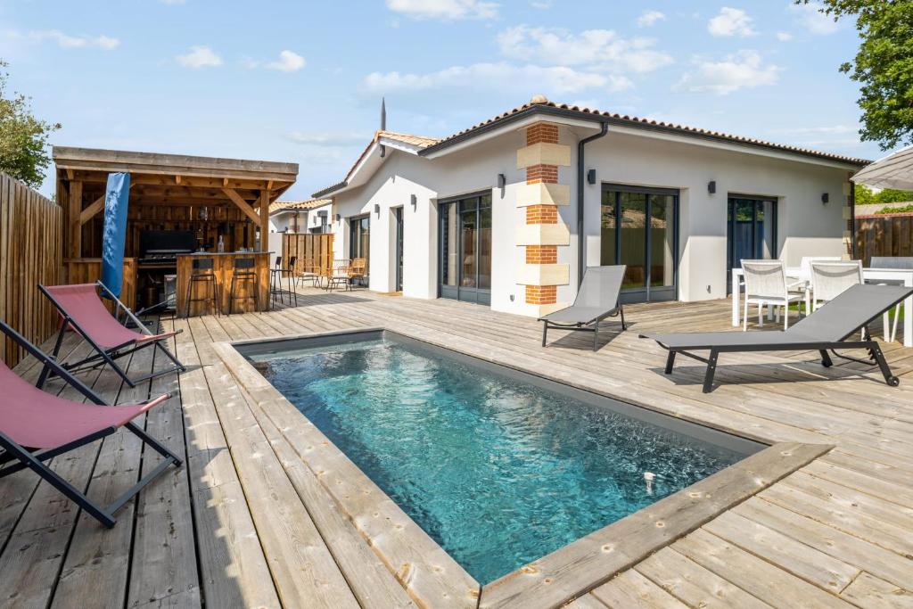 une cour arrière avec une piscine et une terrasse en bois dans l'établissement Villa La Hume - Welkeys, à Gujan-Mestras