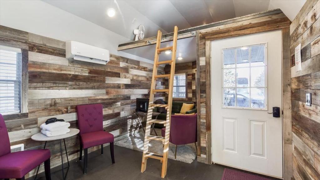 a room with a wooden wall with chairs and a ladder at The Huckleberry A Teton Tiny Home in Driggs