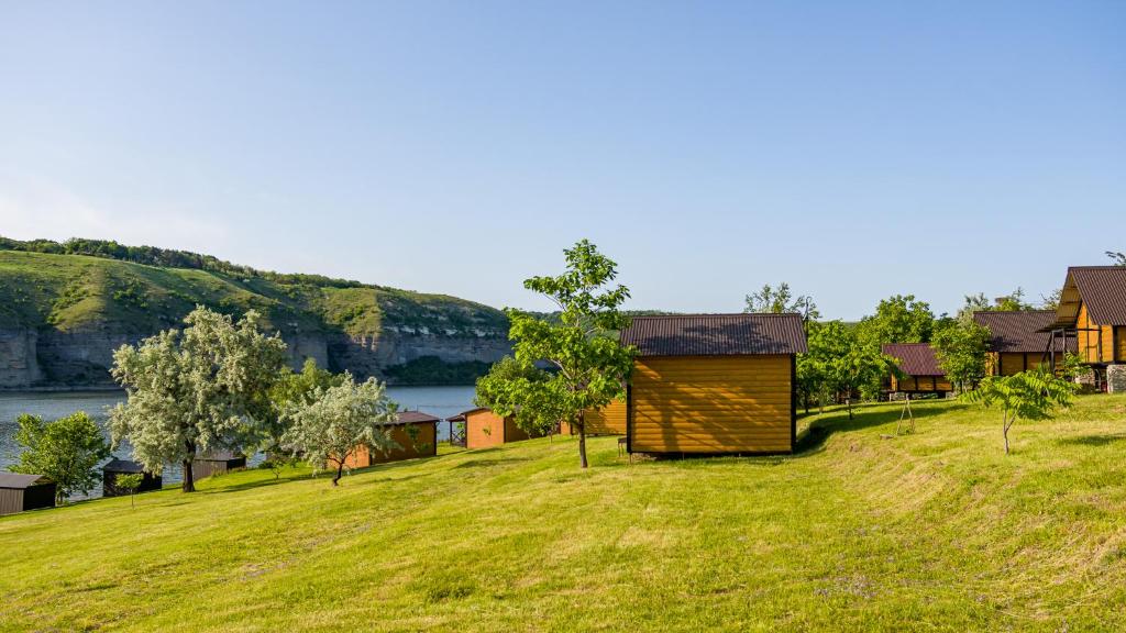 a small building on a grassy hill next to a river at Каньон in Hrushivtsi