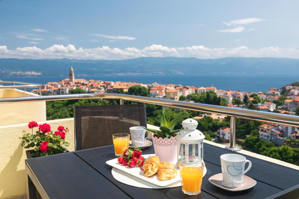 a table with breakfast food on a balcony with a view at Apartman Jelena in Vrbnik