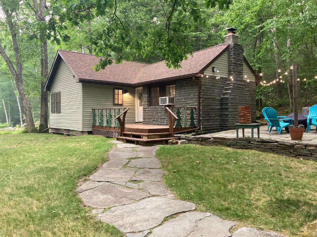 een blokhut met een terras en een patio bij Cute private Wooded Cabin near the big lake in Tafton