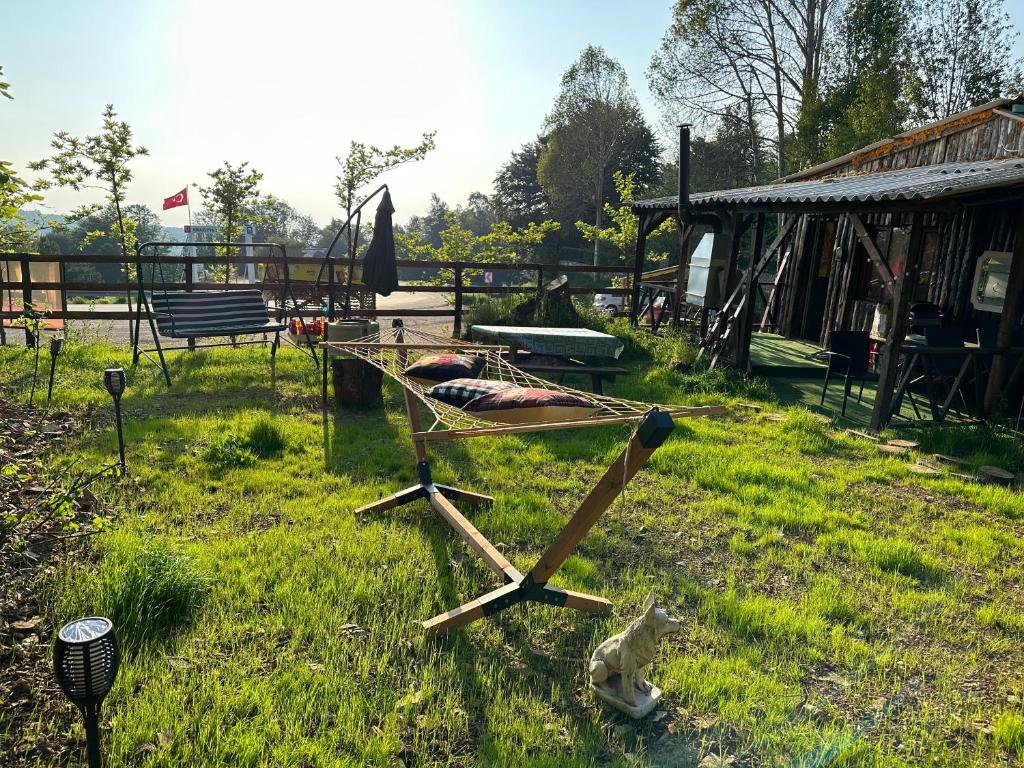 einen Holzstuhl, der im Gras im Hof sitzt in der Unterkunft Bear House Uludağ Bungalov in Hüseyinalan