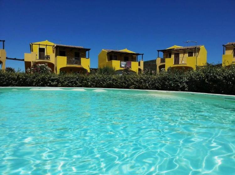 un grupo de casas amarillas con una piscina de agua en Rosamarina, en Viddalba