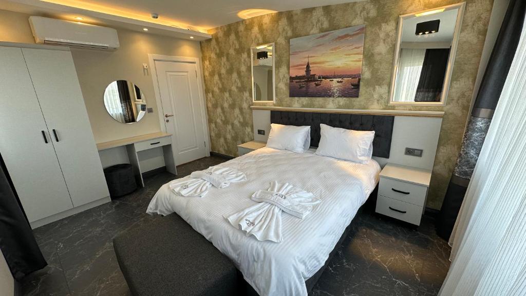 una camera da letto con un letto con lenzuola e asciugamani bianchi di Mar Boutique Apartment a Istanbul