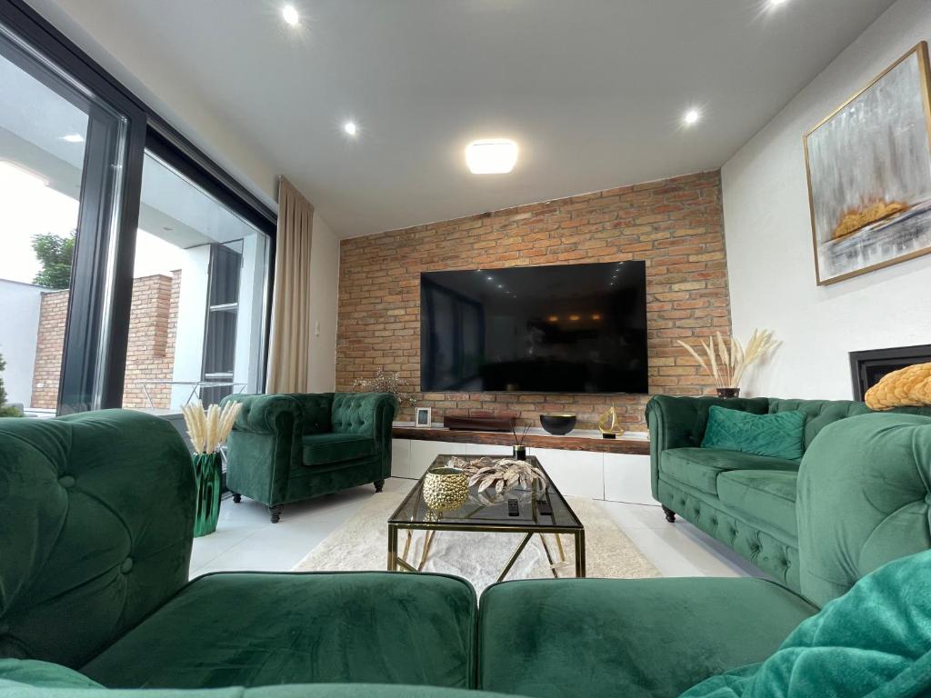 sala de estar con muebles verdes y TV de pantalla plana en Luxurious Panorama House with Pool and Sauna en Budaörs