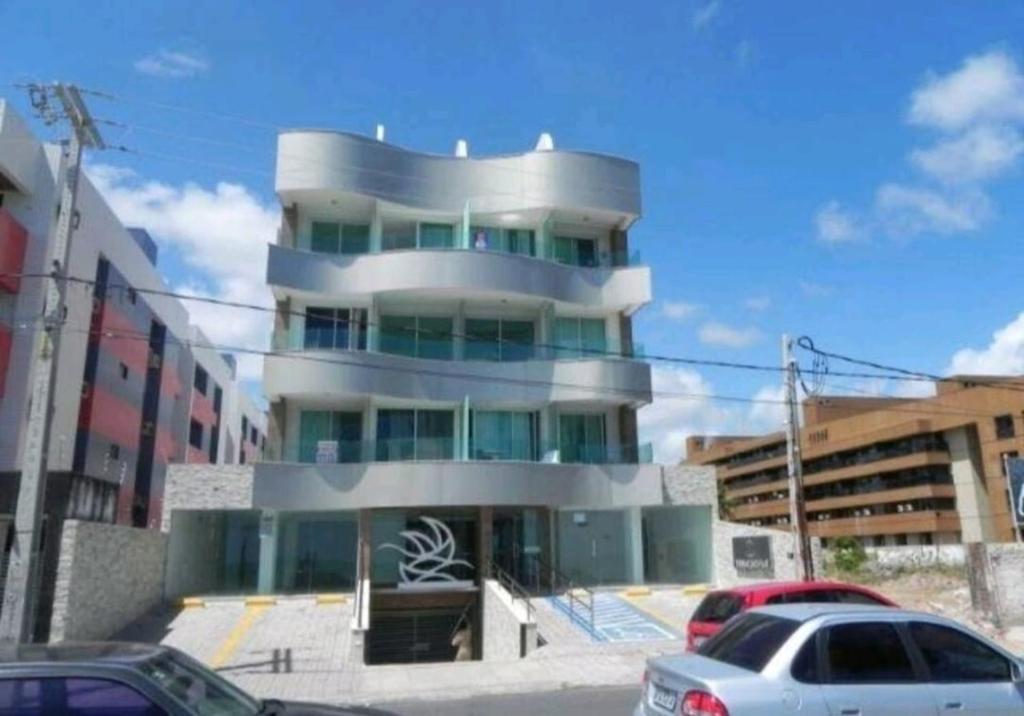a tall building with cars parked in front of it at Studio completo na praia de Manaíra, apt 213 in João Pessoa