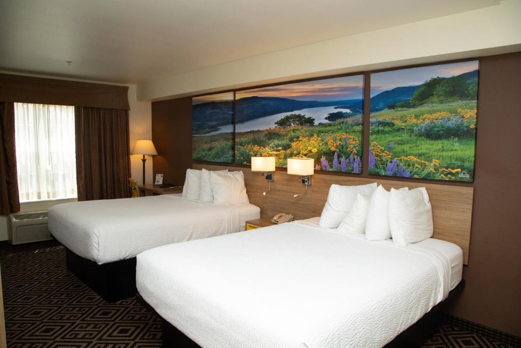 two beds in a hotel room with a painting on the wall at Days Inn by Wyndham Manitou Springs in Manitou Springs