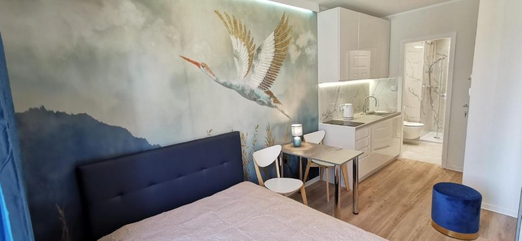 1 dormitorio con 1 cama y una pintura de pájaro en la pared en WOW FLOU Przystań Letnica Apartamenty 700m plaża, en Gdansk