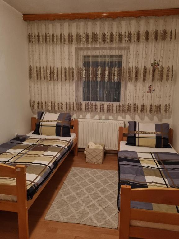 een slaapkamer met 2 bedden en een raam met gordijnen bij Ferienwohnung Sabina in Bosanska Krupa