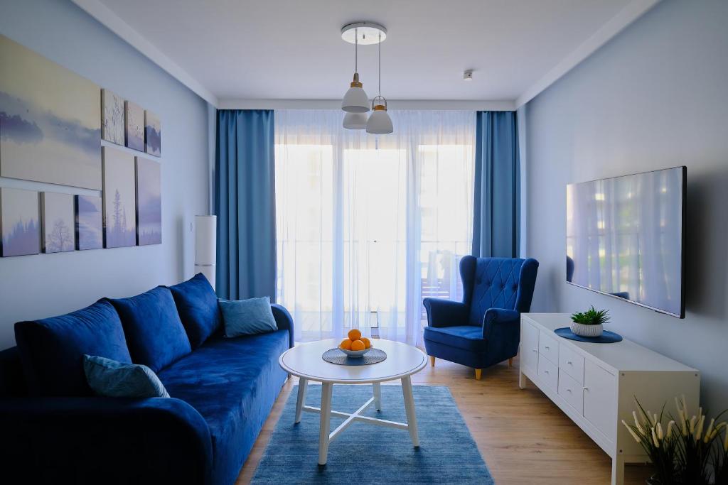 a living room with a blue couch and a table at Riverside Dziwnów Apartament i SPA in Dziwnów