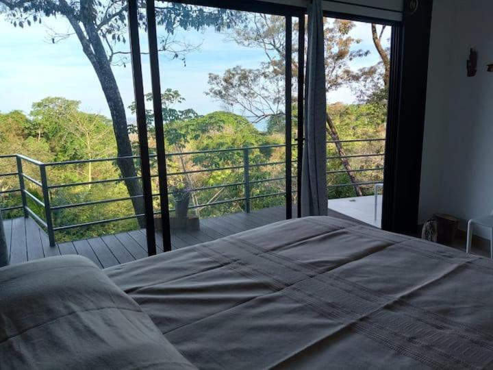 1 dormitorio con 1 cama frente a una ventana grande en Laurel Jungle & Ocean en Santa Teresa Beach