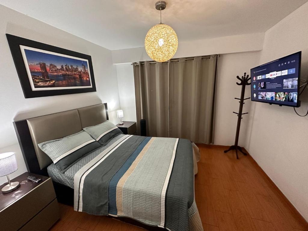 a bedroom with a bed and a tv on the wall at Hermoso Departamento en Guardia Civil - Chorrillos in Lima