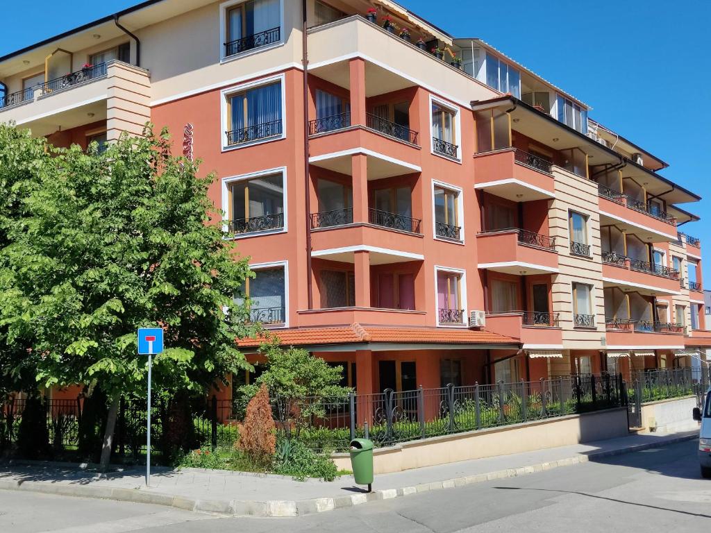 a tall orange building with balconies on a street at Villa Rossa in Ravda