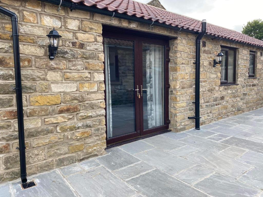 ein Steinhaus mit einer Holztür und einer Terrasse in der Unterkunft Wagtail Cottage in Cloughton