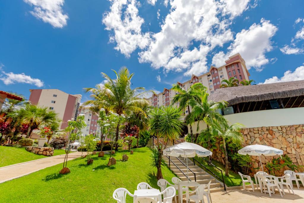 ośrodek wypoczynkowy z białymi krzesłami, stołami i palmami w obiekcie Hotsprings Suite Hotel w mieście Caldas Novas