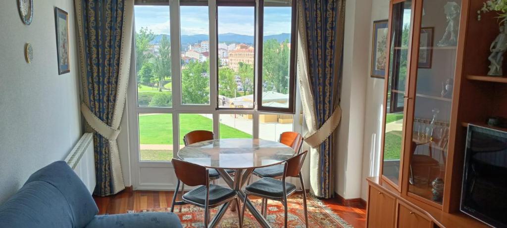 stół i krzesła w pokoju z dużym oknem w obiekcie APARTAMENTO AVELINA w mieście Monforte de Lemos