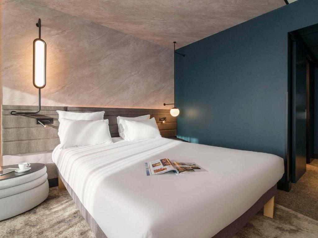 鹿特丹的住宿－鹿特丹布萊恩諾富特酒店，卧室配有一张大白色床,上面有杂志