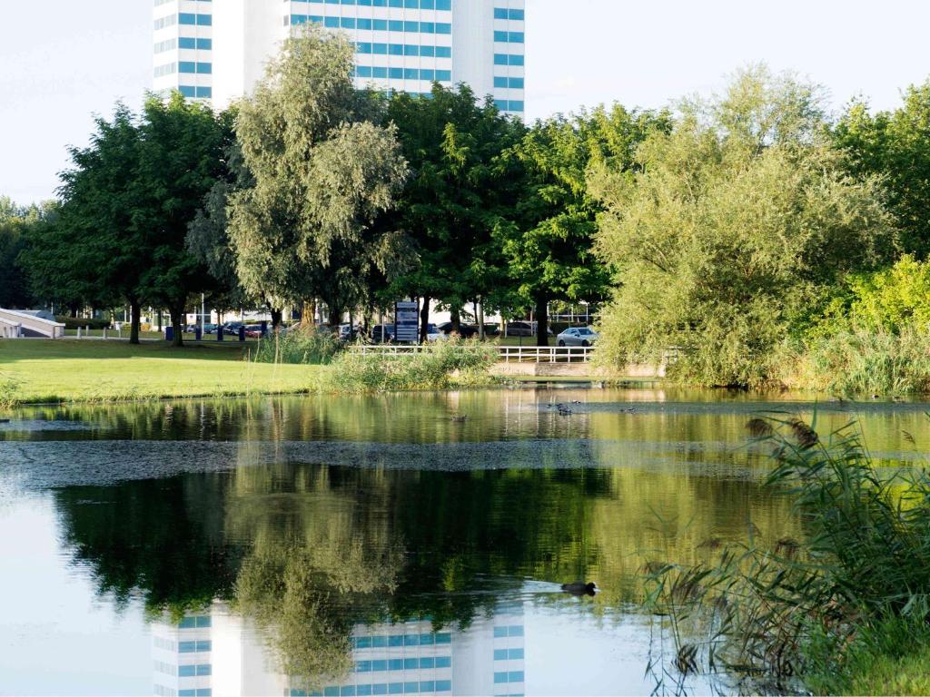 uma vista para um lago num parque com um edifício em Novotel Rotterdam Brainpark em Roterdã