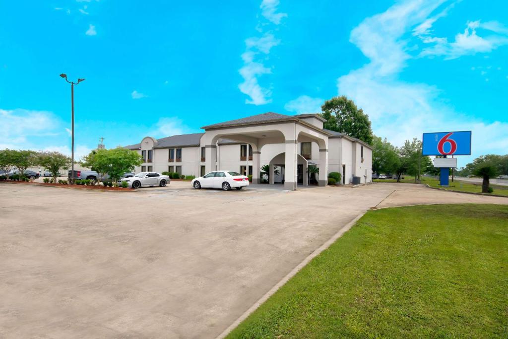a building with cars parked in a parking lot at Motel 6-Abbeville, LA in Abbeville