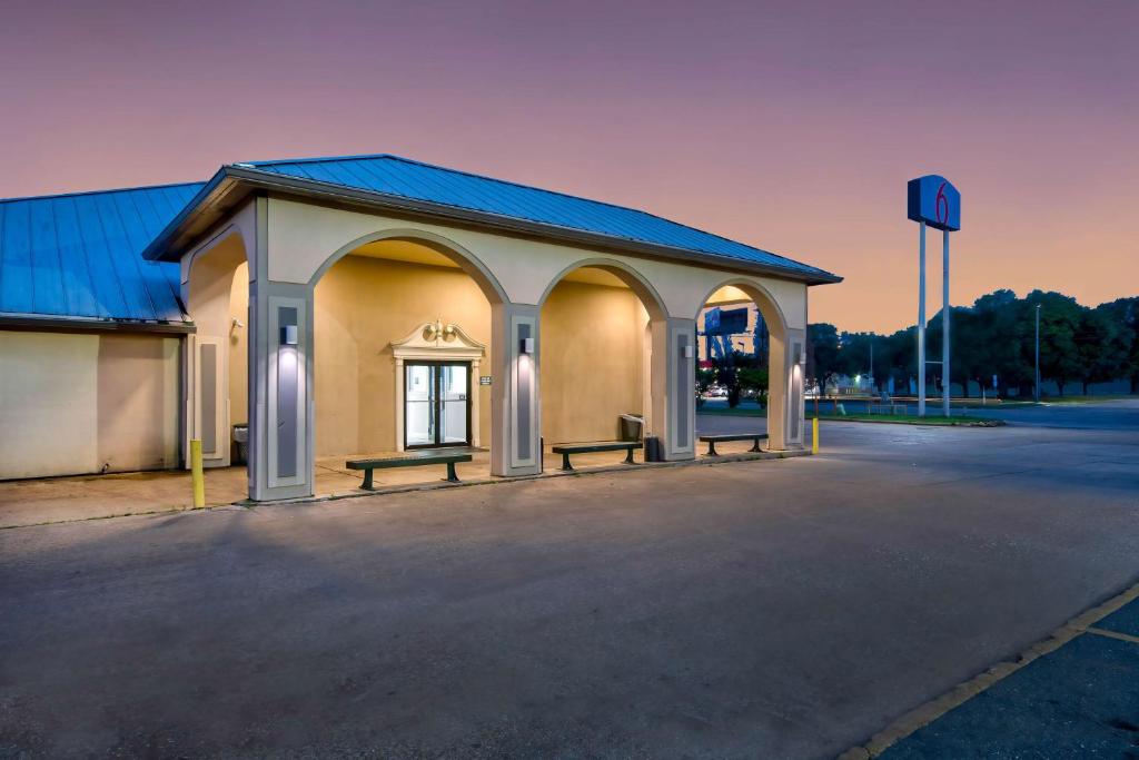 un edificio con due panchine in un parcheggio di Motel 6 Bossier City, La a Bossier City